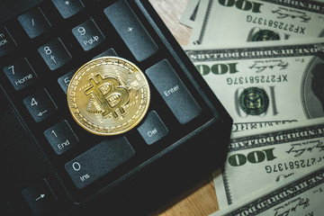 Bitcoin gold coin (cryptocurrency) on keyboard and us dollar - can use for financial and business background