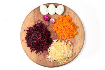 Ingredients for a vinaigrette on a cutting board - carrots, beets, potatoes, onions and chicken eggs