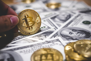Man or Woman holding Bitcoin gold coin (cryptocurrency) on us dollar - can use for financial and business background