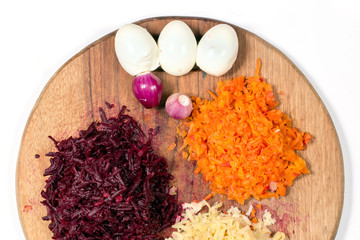 Ingredients for a vinaigrette on a cutting board - carrots, beets, potatoes, onions and chicken eggs