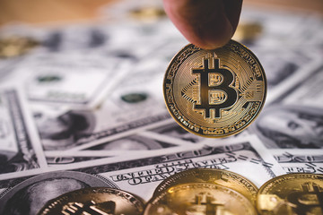 Man or Woman holding Bitcoin gold coin (cryptocurrency) on us dollar - can use for financial and business background