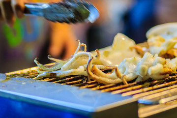 Closeup of Grilling squid, the Exotic Street foods at night market in Thailand. The squid grilled on fire for seafood buffet in the restaurant.