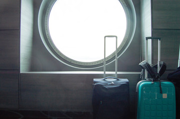 Two suitcases for traveling in front of the round porthole of the ship, the concept of leisure or...