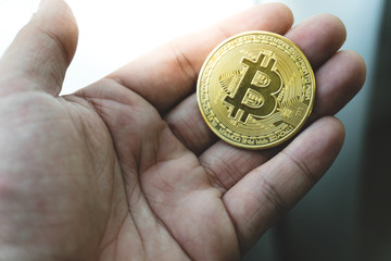 Man or woman holding Bitcoin gold coin (cryptocurrency) in hands - can use for financial and business background