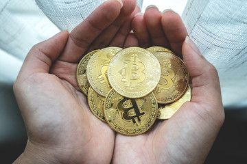 Man or woman holding Bitcoin gold coin (cryptocurrency) in hands - can use for financial and business background