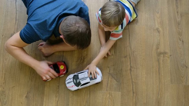 Family concept. Boy and dad playing with cars on wooden floor. Father with son. Directly above view