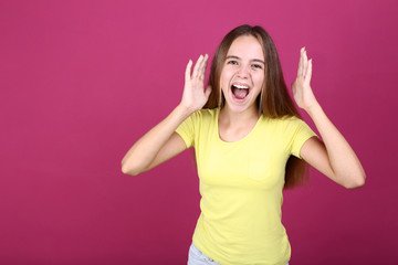 Young screaming girl in yellow t-shirt on pink background