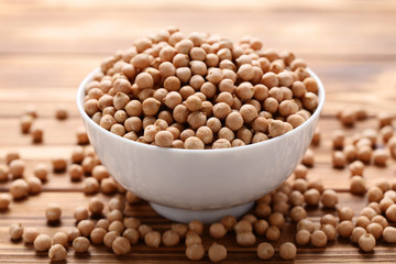 Chickpeas in white bowl on brown wooden table