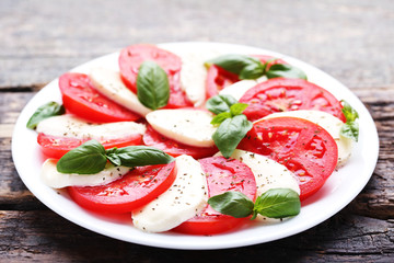 Mozzarella, tomatoes and basil leafs on grey wooden table