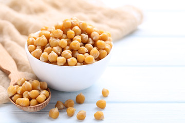 Chickpeas in bowl and spoon on wooden table