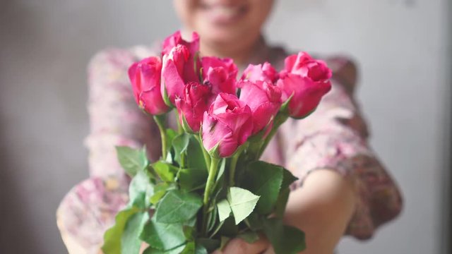 Asian lady with smile gives a bouquet of pink roses to you. front of camera. for love one.