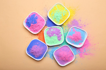 Colorful holi powder in bowls on beige background