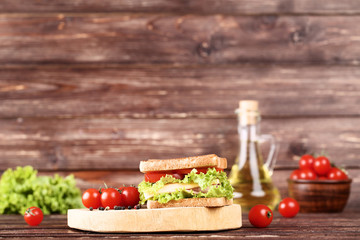 Tasty sandwich with fresh vegetables on brown wooden table