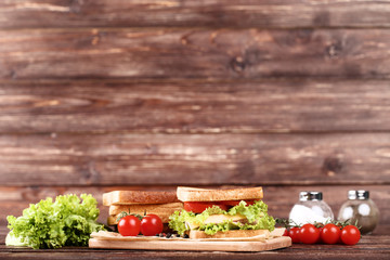 Tasty sandwiches with fresh vegetables on brown wooden table