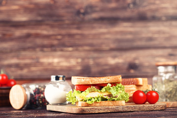 Tasty sandwich with fresh vegetables and spices on brown wooden table