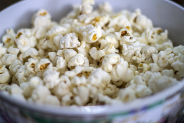 Popcorn in a bowl on blue background, top view