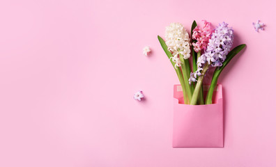 Spring hyacinth flowers in pink postal envelope over punchy pastel background with copy space. Top view, flat lay. Banner. Spring, summer or garden concept. Creative layout.