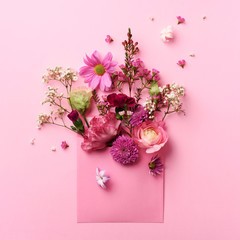 Pink envelope with spring flowers. Floral composition, creative layout. Flat lay, top view. Spring, summer or garden concept. Present for Woman day. Square crop