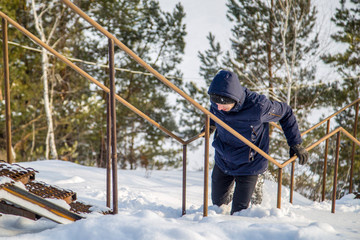 young man climbs the stairs uphill in winter