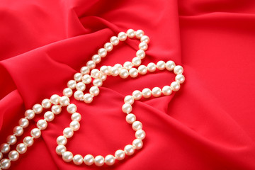 Pearl necklace on red satin fabric