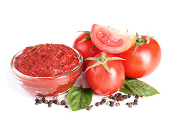 Ketchup in bowl with tomatoes and basil leafs isolated on white background