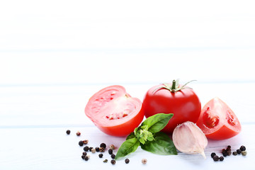 Ripe tomatoes with basil leafs and garlic on wooden table