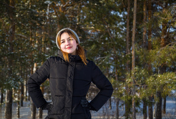 Portrait of a young beautiful girl in the winter against the background of a coniferous forest