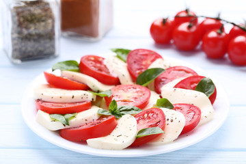 Mozzarella, tomatoes and basil leafs on wooden table