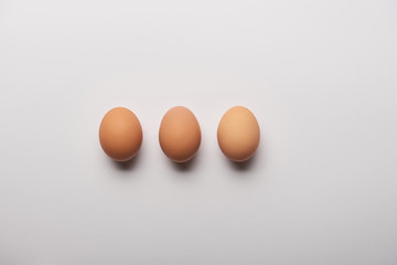 flat lay with three organic eggs on grey background