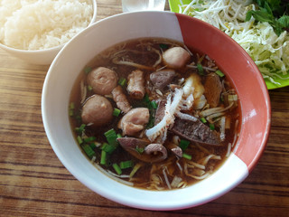 Chinese noodle mixed with meat, meatballs served in white ceramics bowl.