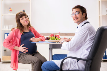 Pregnant woman visiting doctor discussing healthy diet