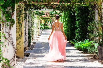 Bright lady bride in a pink wedding dress in a tropical garden alley. Wedding day photo session, the main day