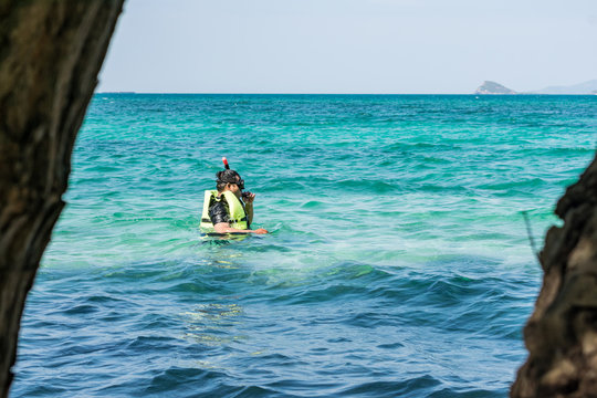 Girl in safety vest learns snorkeling.