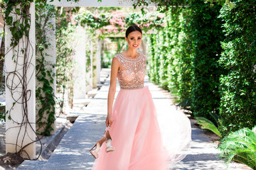 Bright lady bride in a pink wedding dress in a tropical garden alley. Wedding day photo session,...