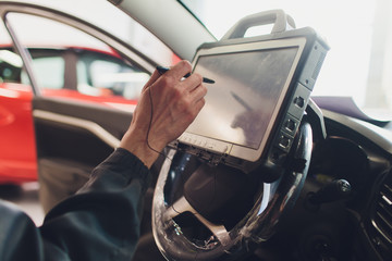 car mechanic maintains a vehicle with the help of a diagnostic computer - modern technology in the...