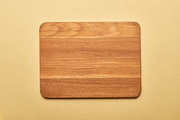 top view of empty wooden chopping board on yellow background