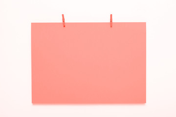 coral paper card on a clothes peg on a white background