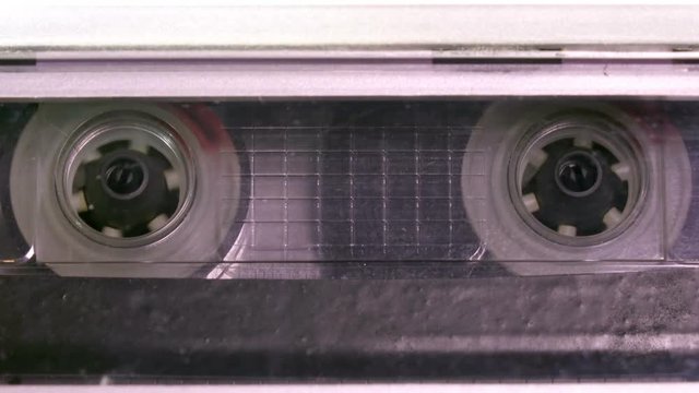 Audio cassette tape in use sound recording in the tape recorder. Vintage music cassette with a blank white label, playing back in the player
