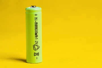 Green battery Nickel metal hydride 1.2 volt, AA size, 600 mAH on yellow background. Close up.