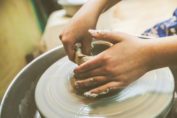 Child hands working with clay on pottery wheel