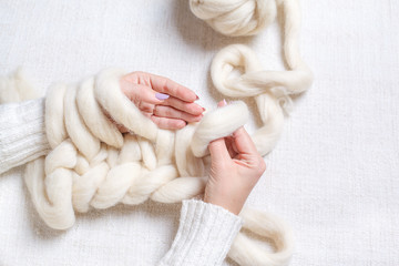 Women's hands knit from thick yarn. Elements of knitting Merino wool