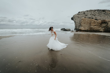 The bride walks on the beach reflected in the water. Panoramic view.