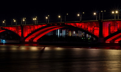 Fototapeta na wymiar Winter night view of the city of Krasnoyarsk. The Communal bridge through the Yenisei River