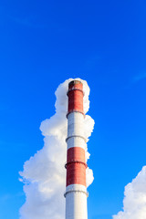 power plant pipes on the background of the panorama of the winter city against blue sky.