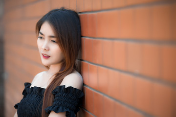 Fototapeta premium Portrait of beautiful asian chic girl wear black dress pose for take a picture on brick wall,Lifestyle of teen thailand people,Modern woman happy concept