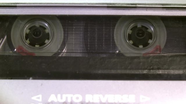 Audio cassette tape in use sound recording in the tape recorder. Vintage music cassette with a blank white label, playing back in the player