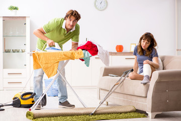 Husband helping leg injured wife in housework