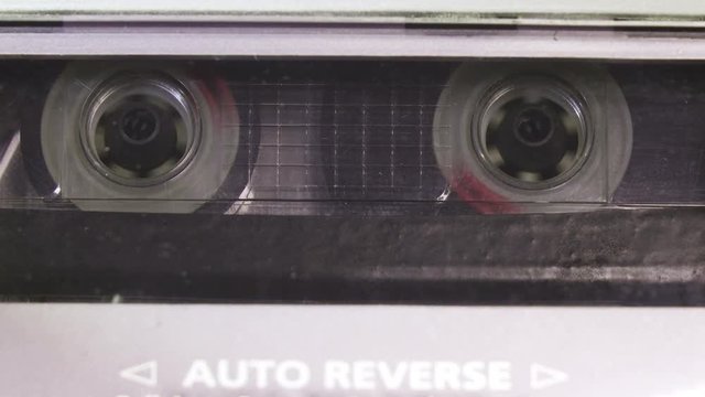 Audio cassette tape in use sound recording in the tape recorder. Vintage music cassette with a blank white label, playing back in the player
