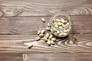 Fototapeta na wymiar Roasted pistachios in a glass jar. Old wooden background. shallow depth of cut