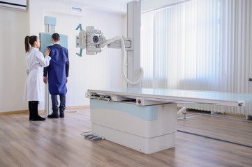 lateral view of a female radiologist doing the paranasal sinuses X-ray to a male patient in...